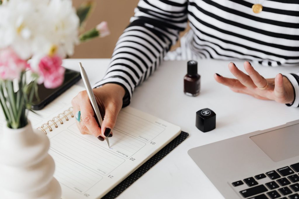 crop woman writing notes while sitting at home