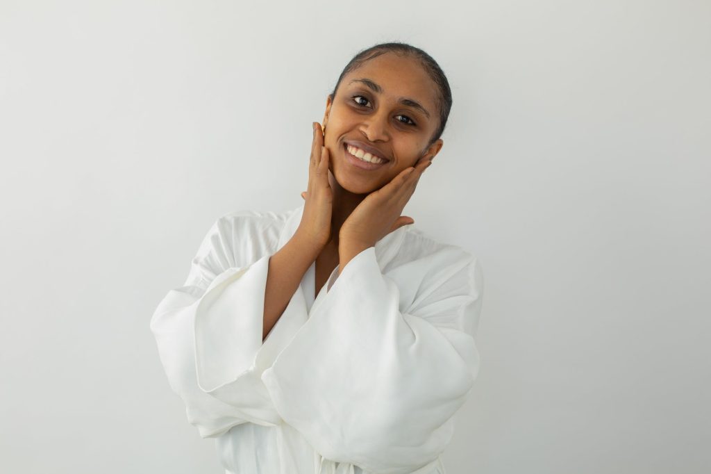 joyful black woman touching face after beauty procedure