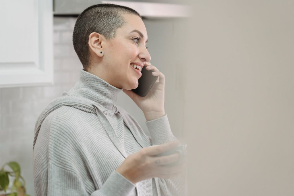 content woman talking on smartphone in kitchen