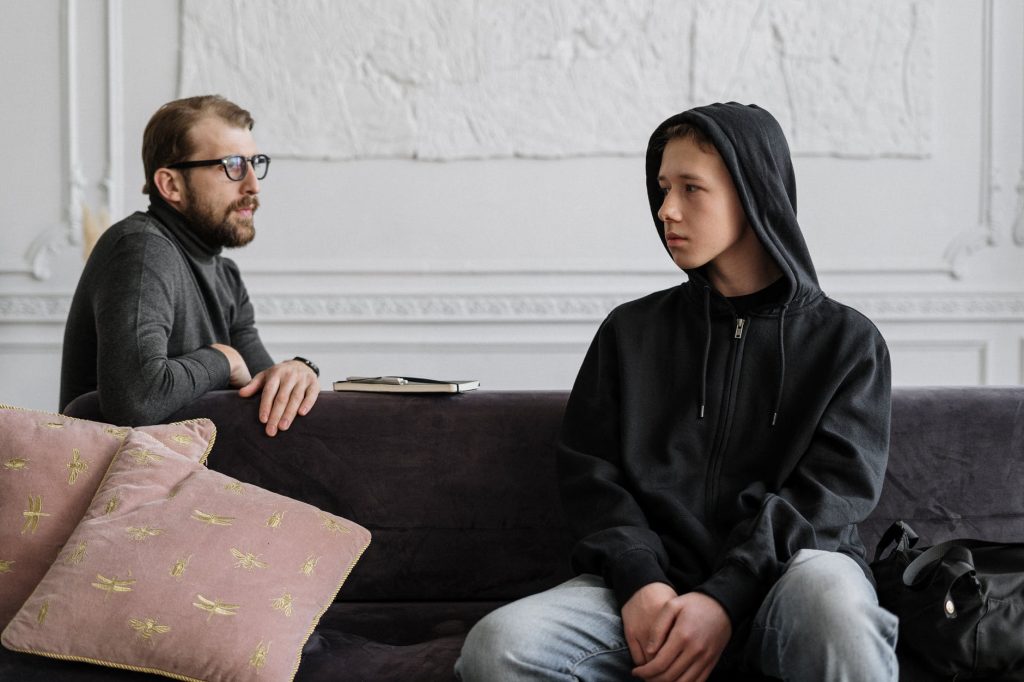 man in black hoodie sitting on brown wooden bench