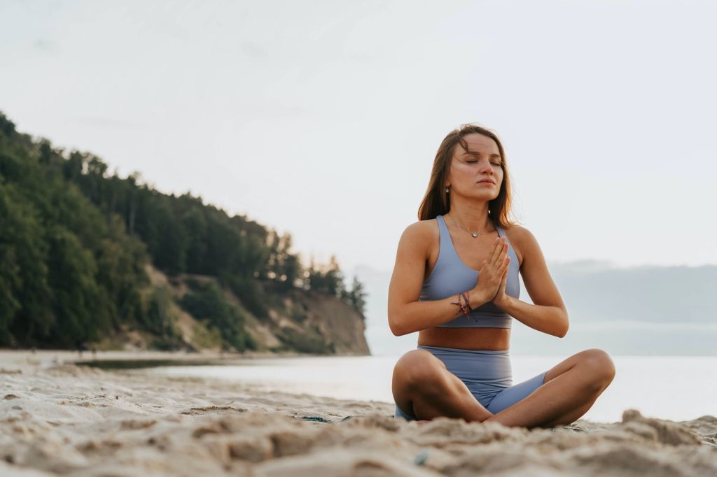 a woman doing a meditation on a beach during morning