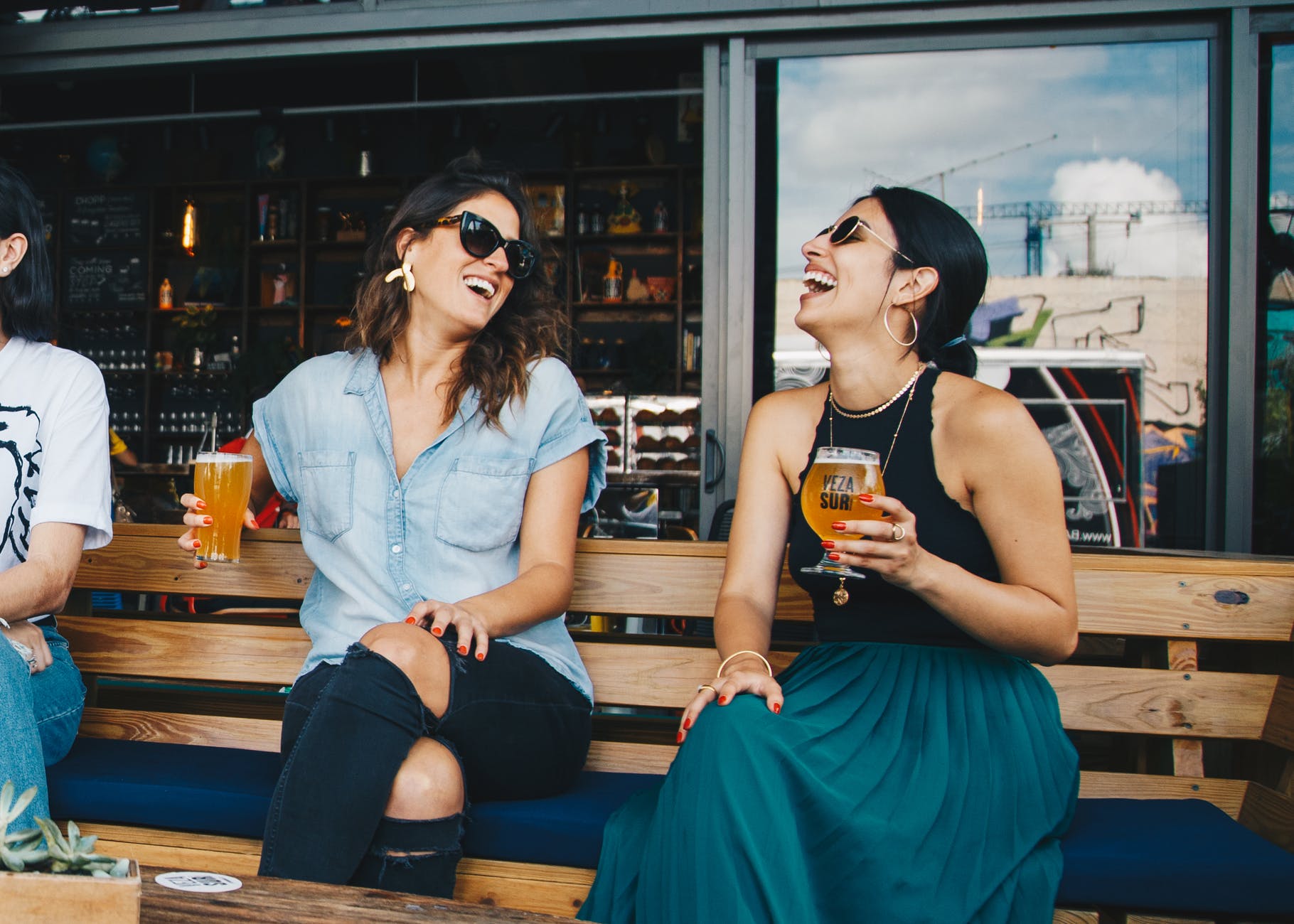 two smiling women sitting on wooden bench