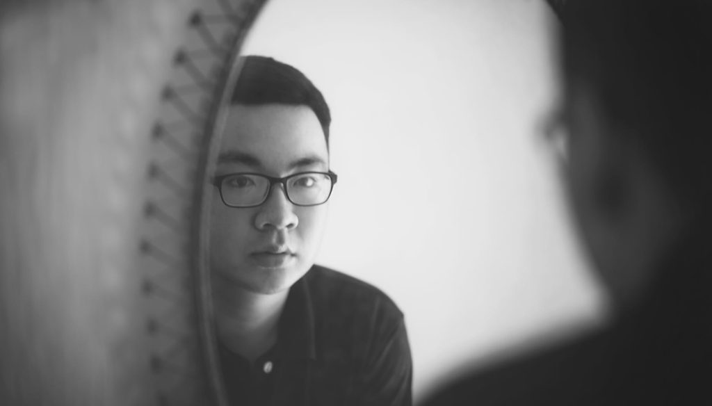 monochrome photography of a man looking in front of mirror