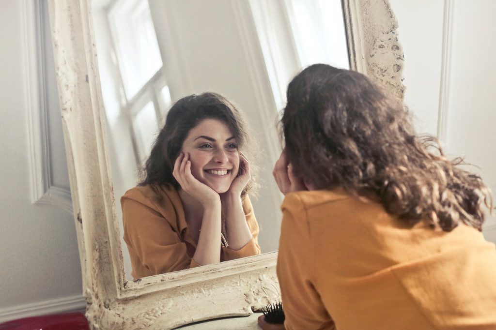 photo of woman looking at the mirror